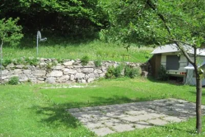 Camping Acquarossa - gefliester Stellplatz neben einem Baum