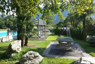 Camping Al Censo - Spielplatz mit kleiner Rutsche und Tischtennisplatte mit Swimmingpool im Hintergrund