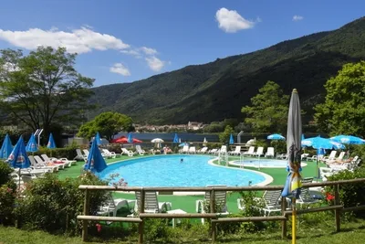 Camping Al Lago - Poolbereich des Campingplatz mit Liegestühlen und Sonnenschirmen