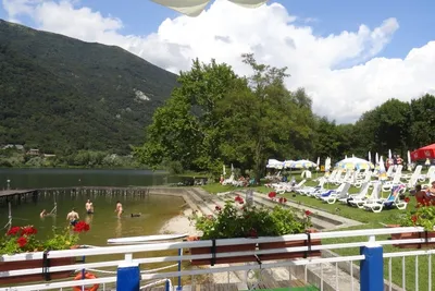 Camping Al Lago - Naturbadebereich des Campingplatzes mit Sonnenliegen am Rand