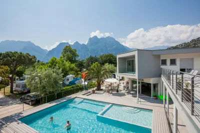 Camping Al Porto - Das Hauptgebäude und der Swimmingpool des Campingplatzes mit Stellplätzen dahinter