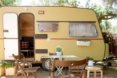 Camping Azahar - Wohnwagen im Schatten mit Tischen und Stühlen