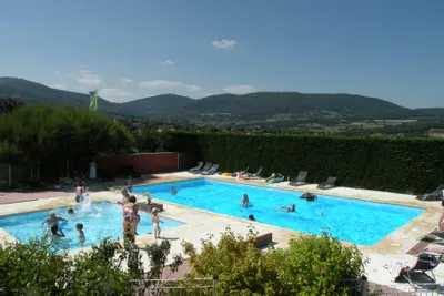 Camping Sites et Paysages Bel' Époque du Pilat - Poolbereich vom Campingplatz mit Liegestühlen in der Sonne und Blick auf den Wildpark