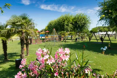 Camping Village Ca' Pasquali - Grünfläche mit Spielplatz und Bäumen