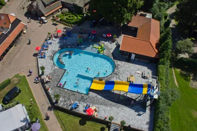 Camping De Koeksebelt - Luftaufnahme des Freibads mit Wasserrutsche, Liegestühlen und Sonnenschirmen