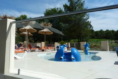 Camping de L' Ayguette - Kinderpool mit Liegen ud Sonnenschirmen im Hintergrund
