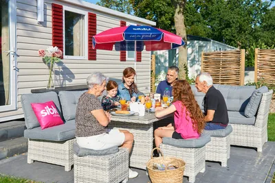Siblu Camping de Oase  Camping De Oase - Campinggäste beim gemeinsamen Frühstücken auf der Terrasse ihres Mobilheims