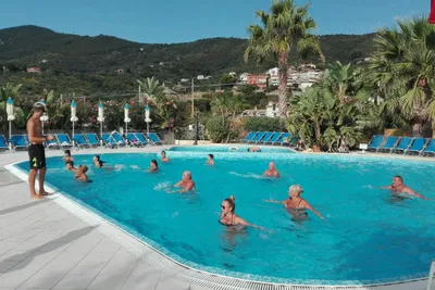 Camping Delfino - Wassergym im Swimmingpool mit Liegestühlen und Sonnenschirmen am Rand
