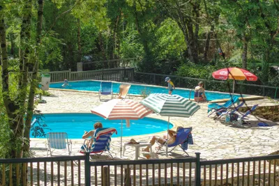 Camping du Ruisseau du Treil  -  Camper am Pool vom Campingplatz mit Sonnenschirmen und Liegestühlen