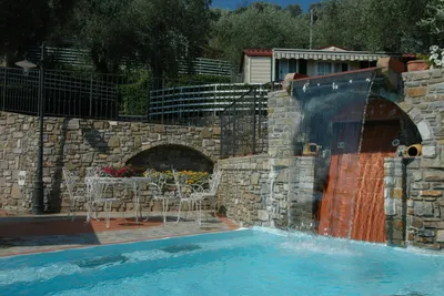Camping Edy - Pool mit Wasserfall und Sitzgruppe in der Sonne