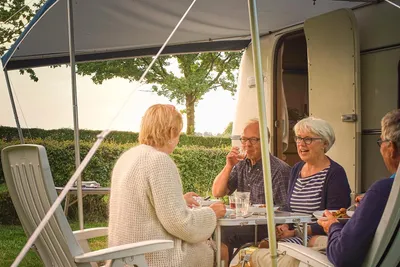 Hoeve de Gastmolen - Camper sitzen vor dem Wohnmobil im Schatten der Markise