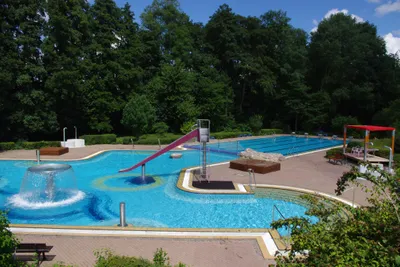 Luftaufnahme des Freibades mit Schwimmbahnen und Wasserrutsche 