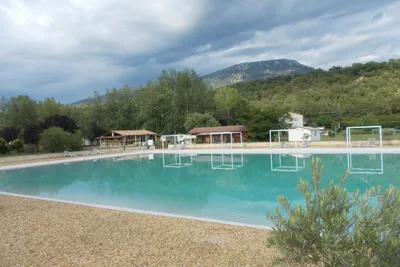 Camping La Célestine - Poolbereich des Campingplatzes mit Liegen am Rand 