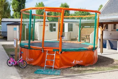 Camping La Pierre Longue  - Trampolin am Sanitärgebäude und den Mobilheimen auf dem Campingplatz