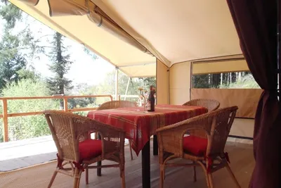 Camping La Pointe - Veranda des Glamping Zelts mit Sitzgelegenheiten darin