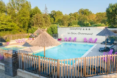 Camping Le Coin Charmant - Blick auf den Pool mit Liegestühlen und Sonnenschirmen