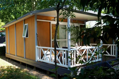 Camping Le Péquelet  -  Mobilheim mit Terrasse zwischen Bäumen auf dem Campingplatz