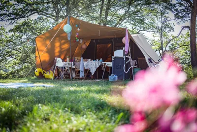 Camping Le Plô - Zelt auf dem Stellplatz mit überdachtem Bereich im Freien und Sitzgelegenheiten