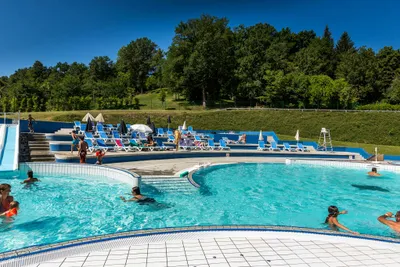 Camping les Aubazines - Poolbereich vom Campingplatz mit Wasserrutsche, Liegestühlen und Sonnenschirmen