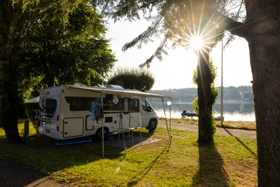 Camping Les Genêts - Standplatz zwischen Bäumen am Wasser
