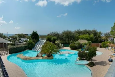 Camping Les Iles  -  Pool vom Campingplatz mit Wasserrutsche, Sonnenschirmen und Liegestühlen