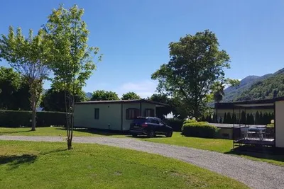 Camping Lido Cannero - Mobilheime zwischen den Bäumen mit Blick auf Berge auf dem Campingplatz