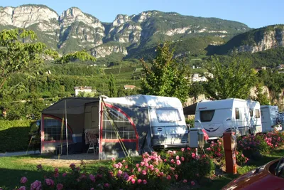 Wohnwagen- und Wohnmobilstellplätze auf der Wiese des Campingplatzes Camping Obstgarten an der Südtiroler Weinstraße mit Gebirge im Hintergrund