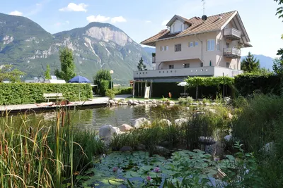 Schwimmteich mit Gebaude und Gebirge im Hintegrund auf dem Campingplatz Camping Obstgarten an der Südtiroler Weinstraße