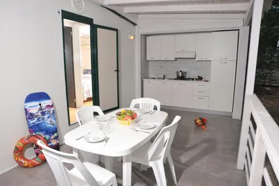 Camping Punta Lunga - überdachte Terrasse eines Mobilheims mit Kochnische und Esstisch