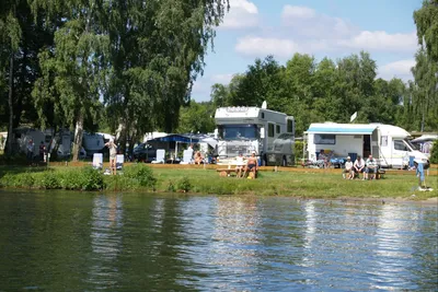 Campingpark Kamerun - Gäste am Wasser vor den Wohnmobilstellplätzen im Grünen auf dem Campingplatz