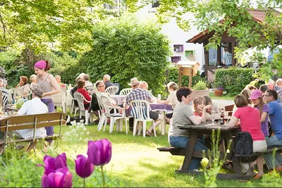 Campingpark Schellental  -  Camper auf der Terrasse vom Restaurant auf dem Campingplatz zwischen Bäumen