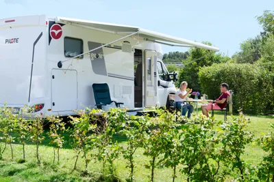 Campingplatz Muschelgrund - Camper sitzen an einem Tisch vor ihrem Wohnmobil auf einem Standplatz