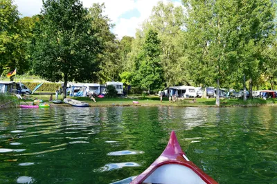 Campingplatz Schachenhorn - der  Wohnwagen- und Zeltstellplatz zwischen Bäumen, von einem Kanu aus aufgenommen