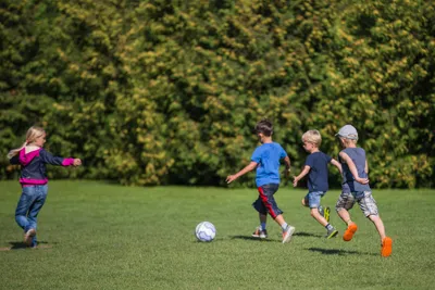 Campingplatz Südstrand  - Fußball spielende Kinder auf grüner Wiese vom Campingplatz