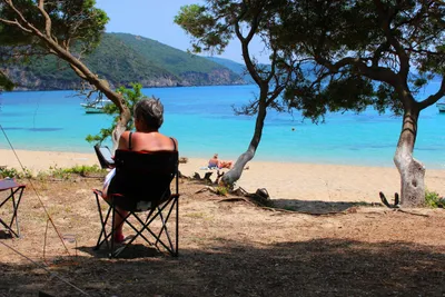 Camping Enjoy Lichnos - Camper sitzen im Schatten mit Blick auf das Meer