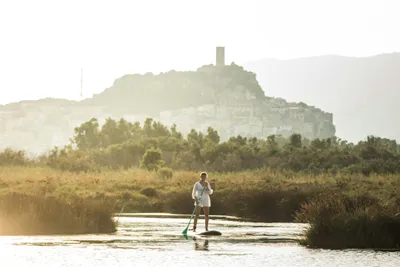 Camping Ermosa  - Stand Up Paddling auf dem Fluss am Campingplatz, La Caletta auf Sardinien im Hintergrund