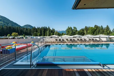 Euro-Camp Wilder Kaiser  -  Pool vom Campingplatz mit Sonnenschirmen und Liegestühlen und mit Blick aufBerge