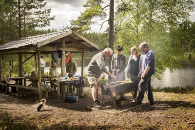 Nordic Camping Hökensås  -  Camper beim Grillen am überdachten Picknicktisch und See vom Campingplatz