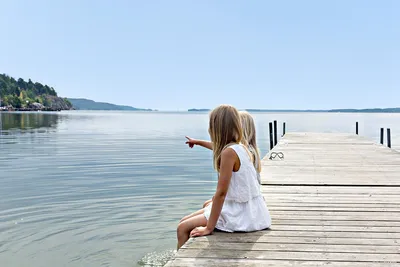 First Camp Kolmården - Kinder sitzen auf dem Pier mit Blick auf Meer auf dem Campingplatz