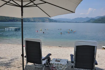 Camping Fleiola - Liegestühle und Sonnenschirme am Strand am Caldonazzo See