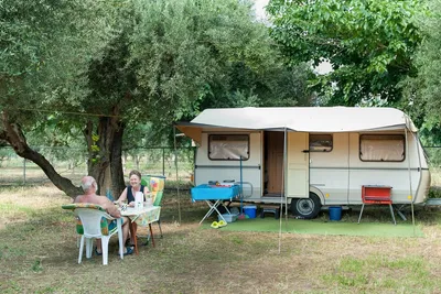 Camping Gythion Bay - Camper sitzen vor dem Wohnmobil im Schatten der Bäume auf dem Campingplatz