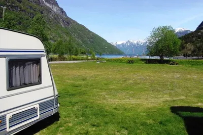 Hellesylt Camping  -  Wohnwagen auf dem Stellplatz vom Campingplatz mit Blick auf den Fjord und schneebedeckte Berge