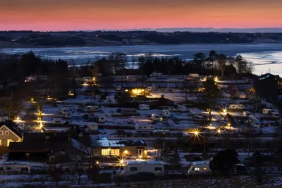 Hjarbæk Fjord Camping - Nachtaufnahme des Campingplatzes im Winter mit dem Wasser des Hjarbæk Fjord im Hintergrund