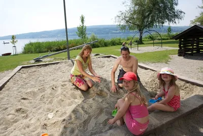 Campingplatz Horn  - Familie im Sandkasten auf dem Spielplatz vom Campingplatz mit Blick auf den See