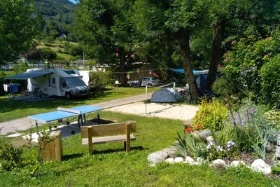 Idéal Camping - Blick auf den Campingplatz mit Standplätzen im Grünen und Tischtennisplatte mit Sitzbank