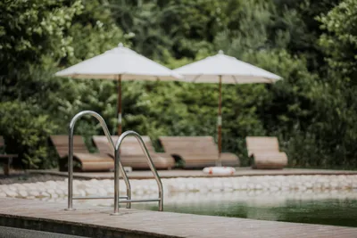 IKUNA Camping Resort - Naturschwimmteich und Liegestühle mit Sonnenschirmen