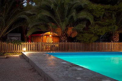 Camping Iria Beach - Pool vom Campingplatz am Abend mit Wohnwagen unter Palmen im Hintergrund