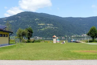 Camping Kölbl - Wiese auf dem Campinggelände mit Kinderspielplatz im Hintergrund am Ossiacher See