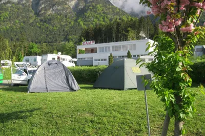 Camping Kranebitterhof - Zelte auf Stellplätzen mit einem Gebäude des Campingplatzes im Hintergrund