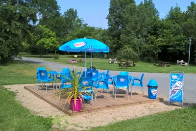 Camping La Fritillaire - eine Terrasse der Snackbar mit Sitzgelegenheiten und Sonnenschirm